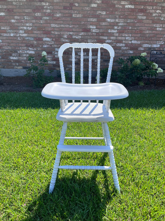 White chair on a grassy area with a brick path